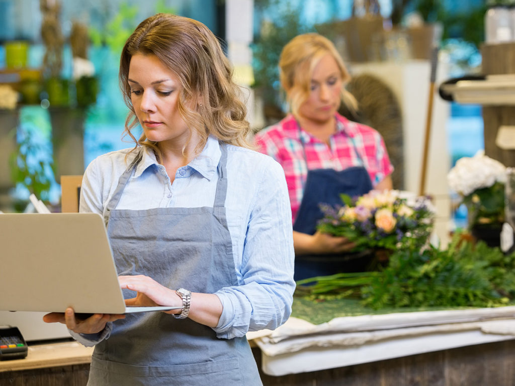 Woman working on laptop in flower shop