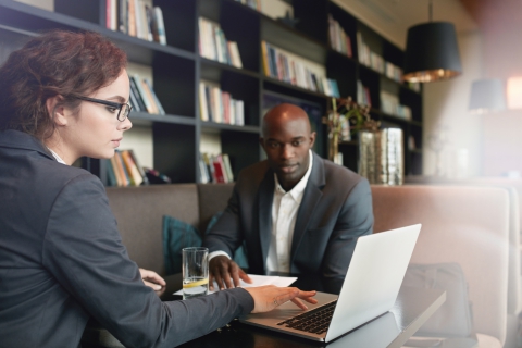 Young businesswoman working on laptop with her business partner while sitting at cafe. Young executives at coffee shop meeting for new business